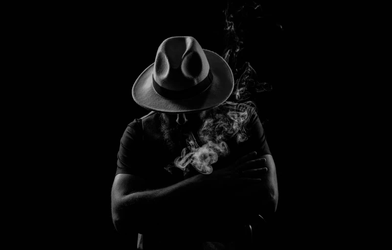 a man wearing a hat and holding a smoking pipe