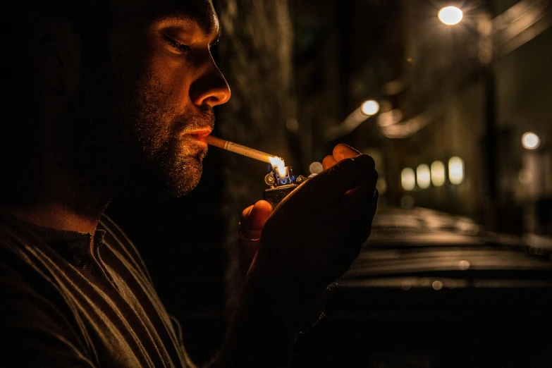 a man lights a cigarette in a darkened area