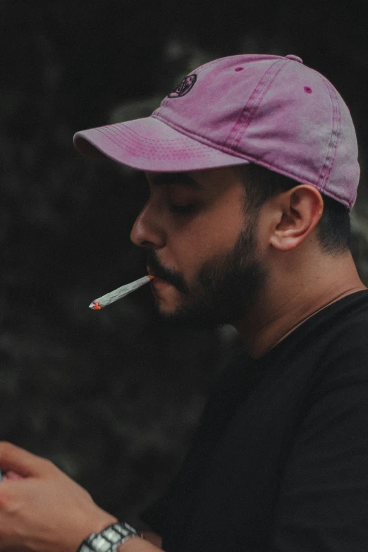 a man smoking a cigarette while wearing a hat