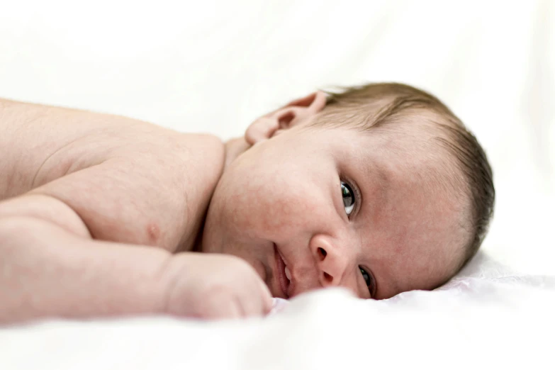 a baby laying down on its side looking at soing