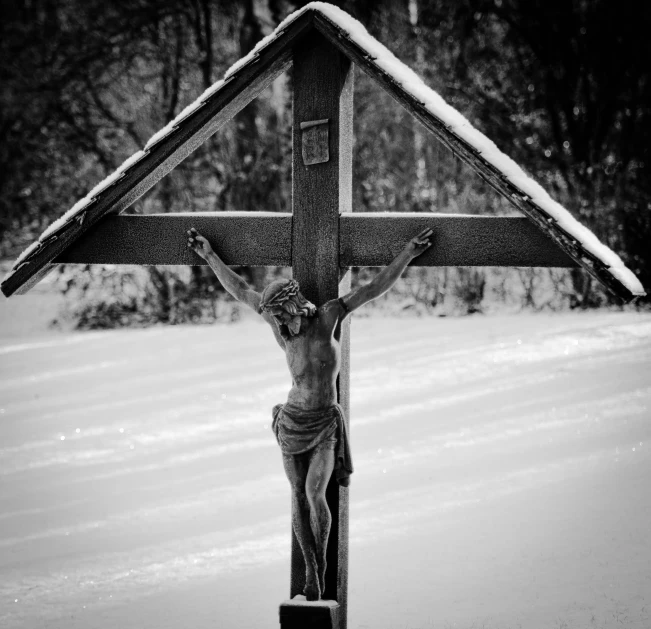 a crucifix sitting in the middle of a snowy road
