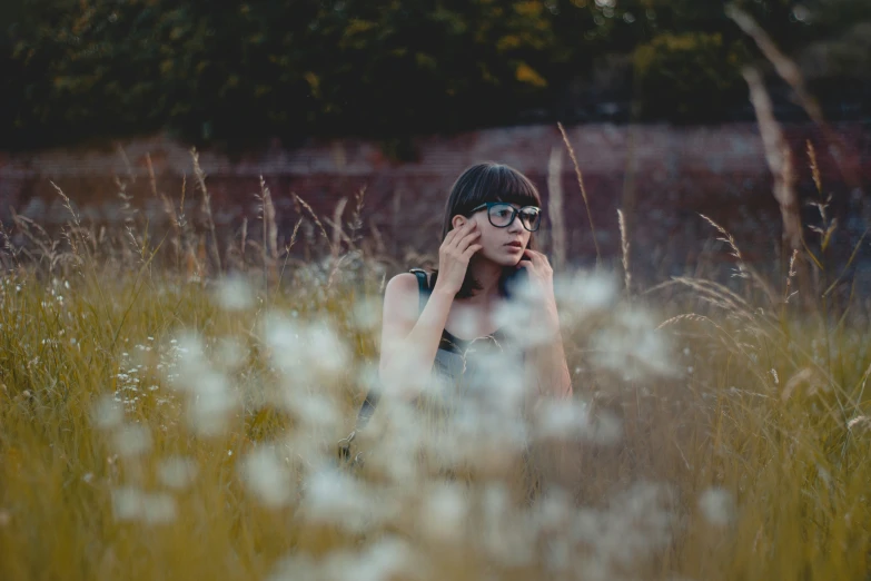 a woman standing in the grass talking on a cellphone