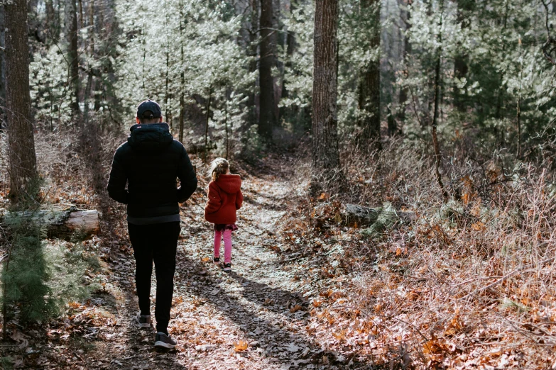 a man and little girl walking in the woods together