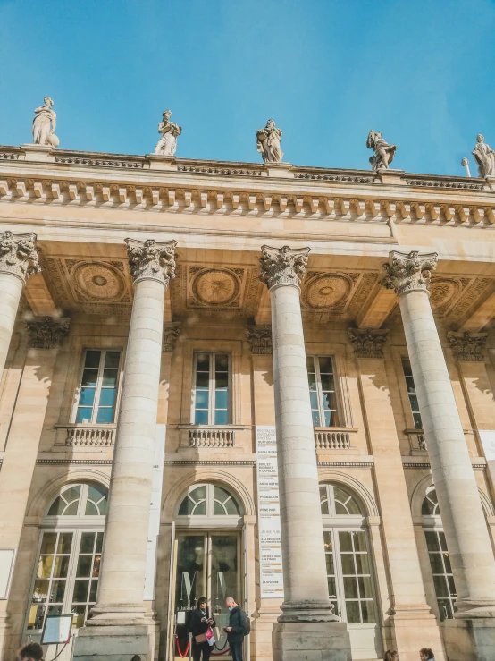 people standing in front of a large building with columns