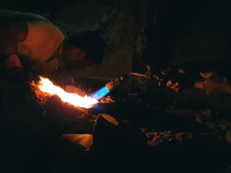 a man sitting in front of a fire with a blue object