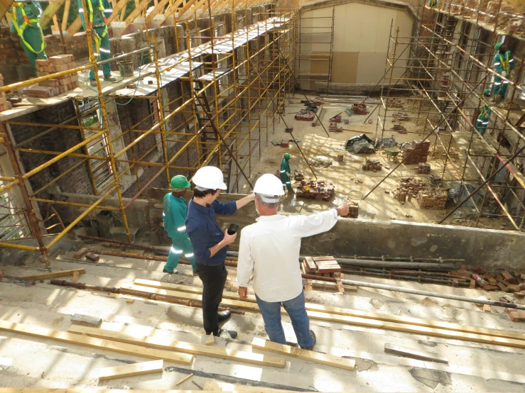 three men working in a building, one on a cell phone