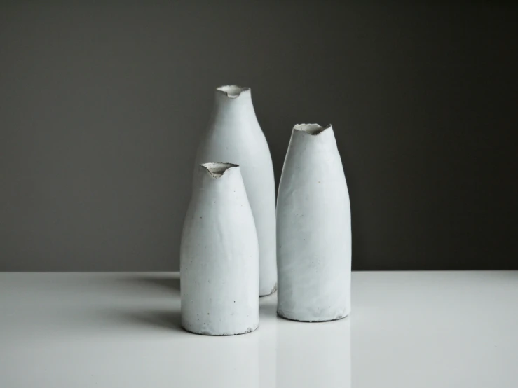 two white vases are standing on the counter