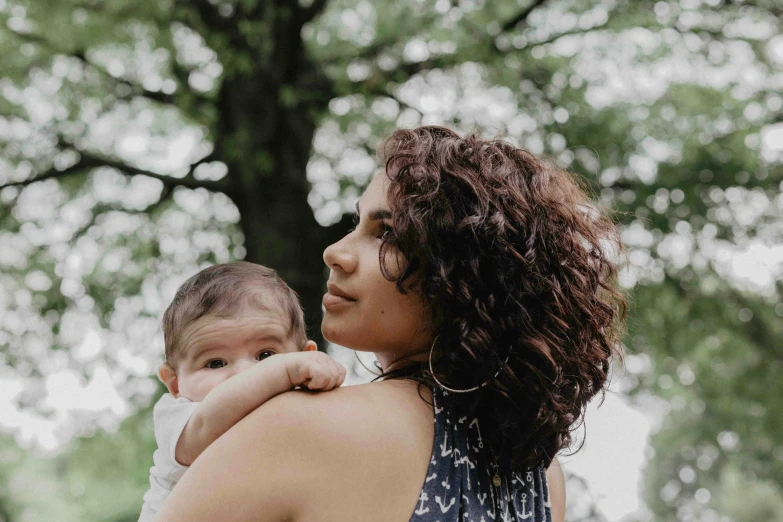 woman carrying a baby outside in a park