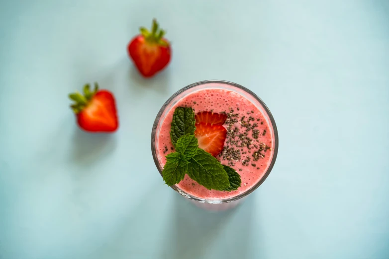 two strawberries and mint are laying around an un - blended drink