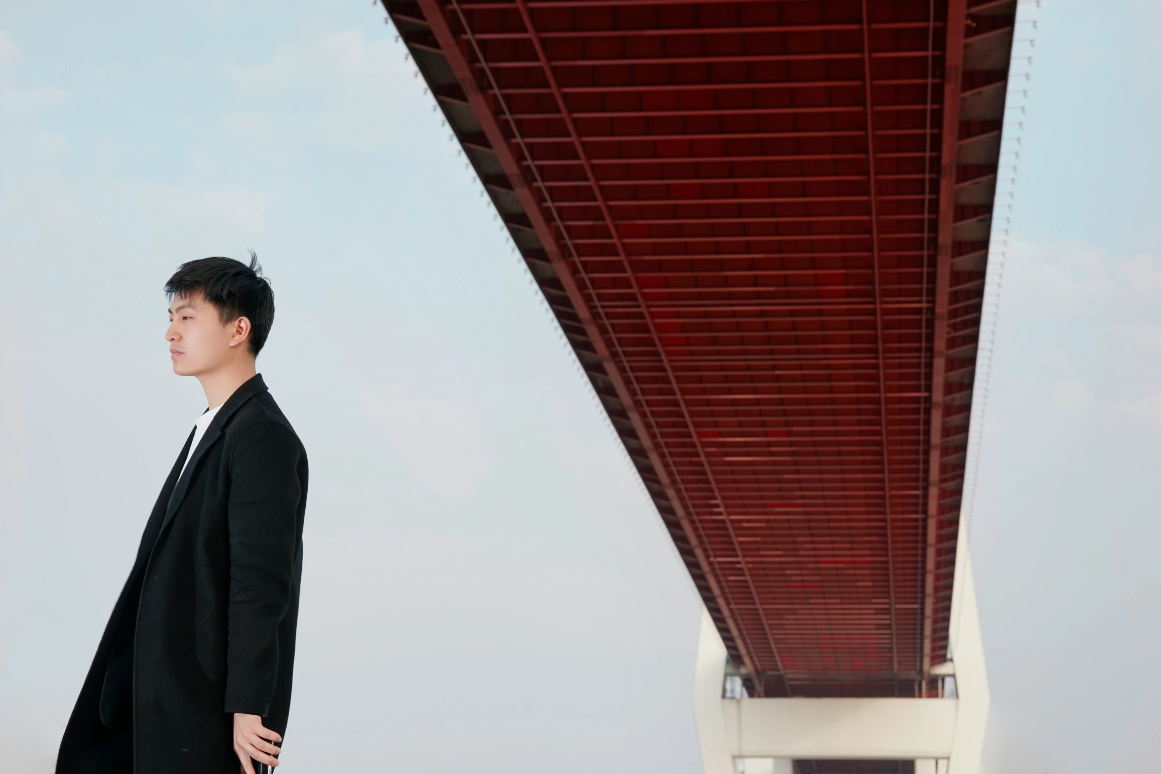 a man in a suit is standing in front of a bridge