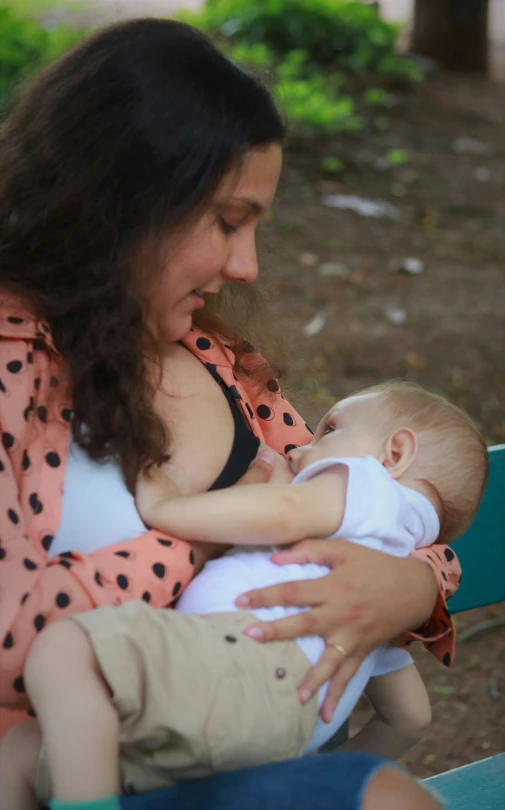 a woman holding a small baby sitting on a bench