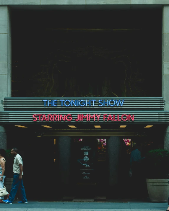 two men walk past an empty theater in the dark