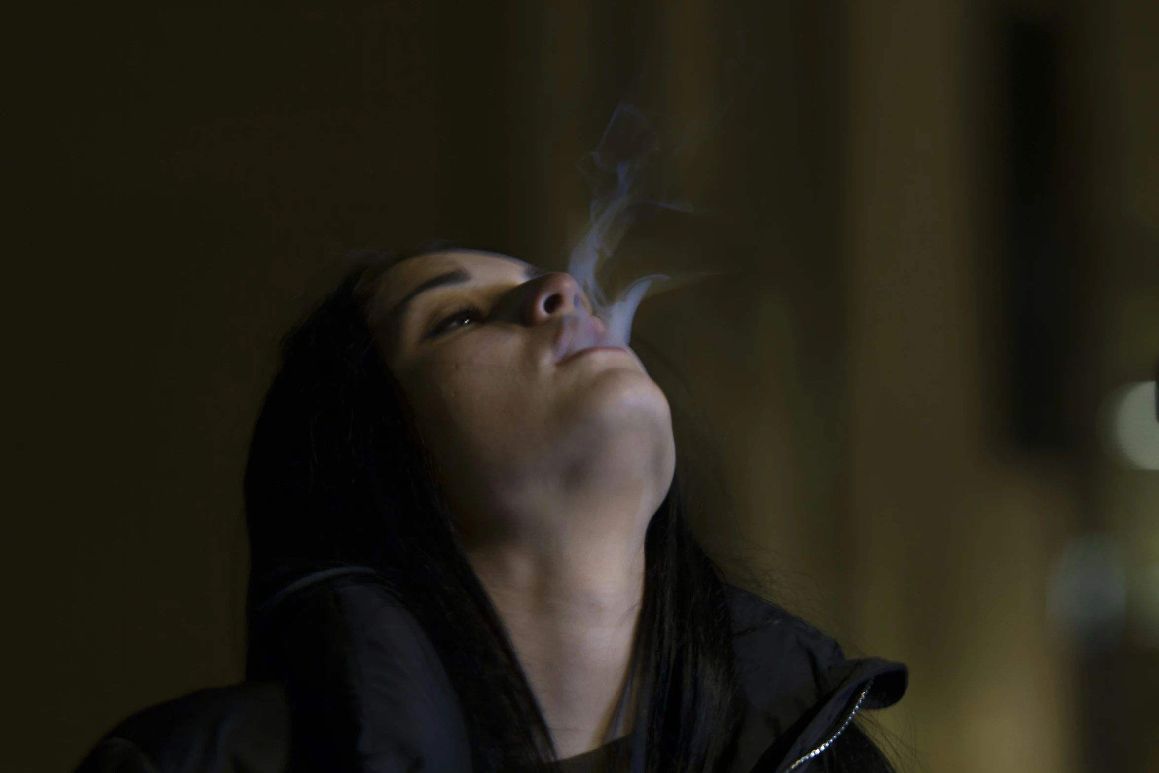 woman looking upward at smoke coming out of her mouth