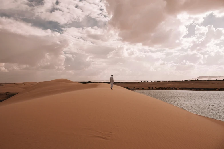 a person on a dirt dune next to water