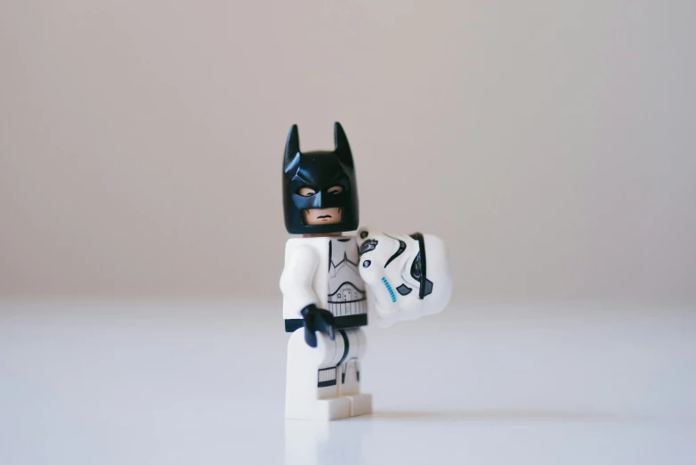 a lego batman holding a cat in his hand