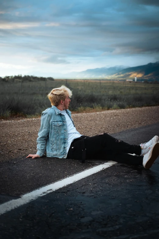 a guy laying on the ground near an open road