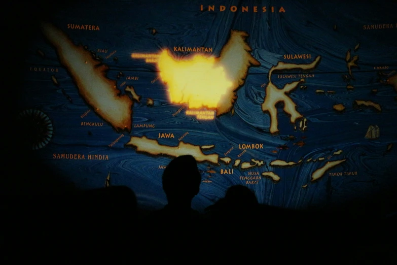 the silhouettes of people are watching a map on television