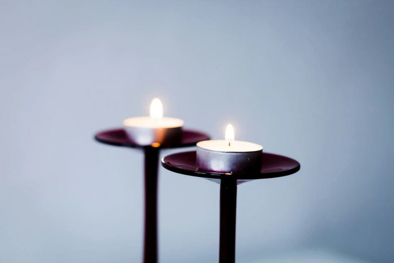 two candle holders on a metal base are white and yellow