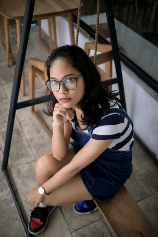 young adult sitting on wooden bench and staring at camera