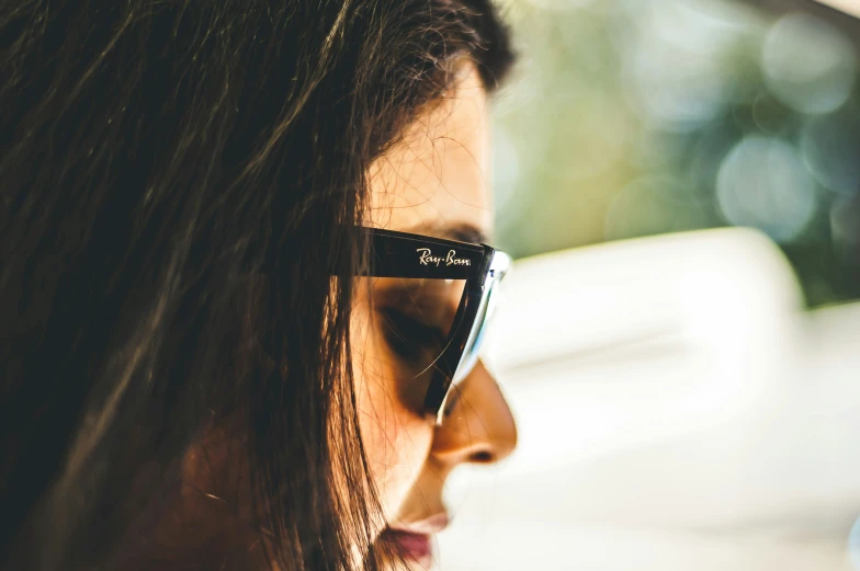 an image of a woman wearing sunglasses looking at her cell phone