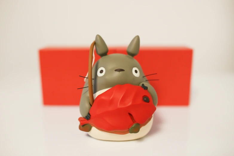 a figurine of a cat holding a red object