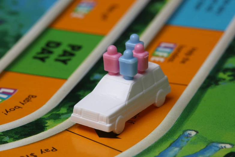 several small toy cars are on an orange and green board game