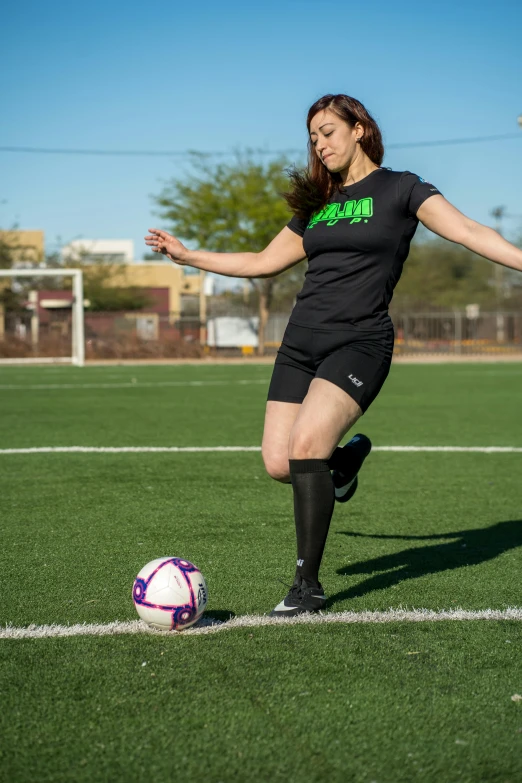 a girl standing in the grass with her foot up on a soccer ball