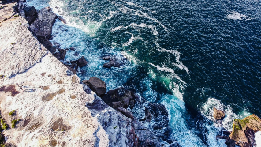 the view from above of rocks, a body of water and cliff cliffs