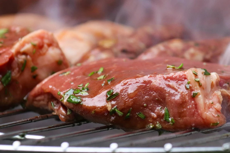 steaks cooking on a bbq grill with meat being cooked