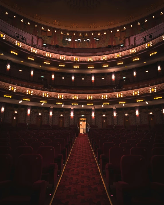 a empty auditorium with an arched ceiling and rows of red chairs