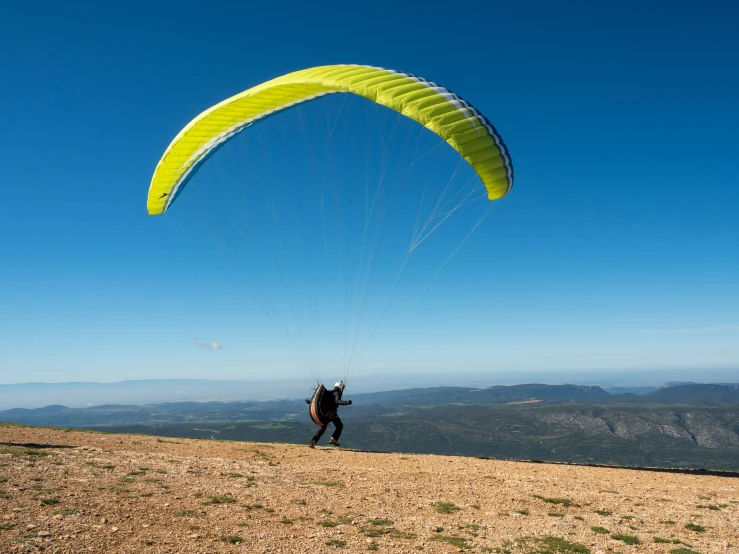 the man is flying a large yellow kite