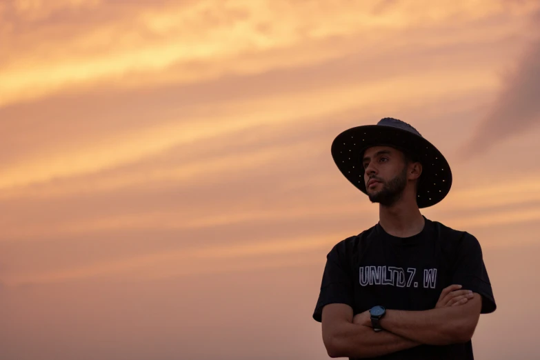 a person in a hat and shirt with arms crossed