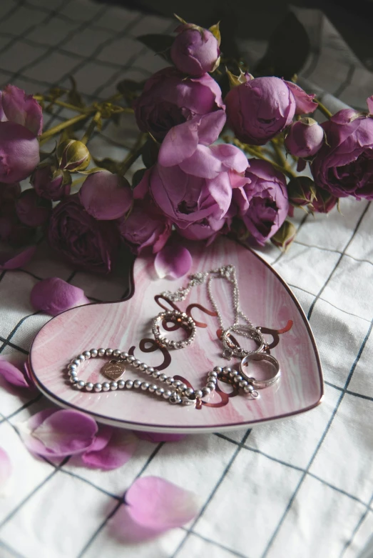 a couple of rings sitting in a pink heart dish