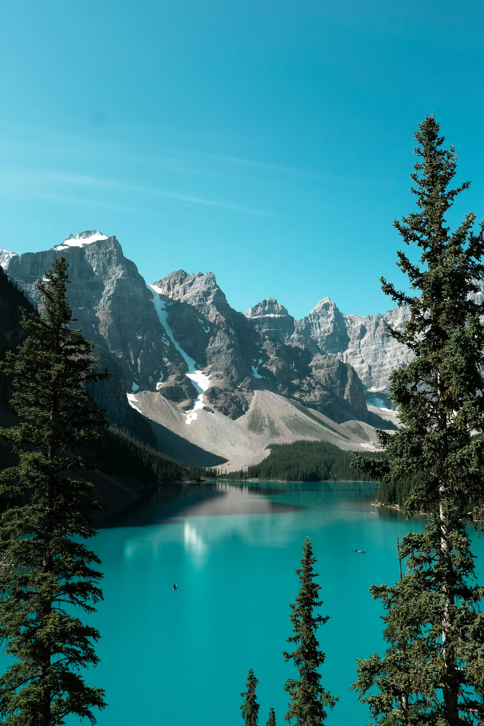 the trees are near the water by the mountains