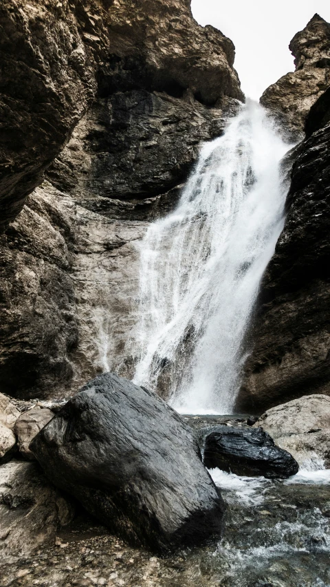 a waterfall with a few big rocks behind it