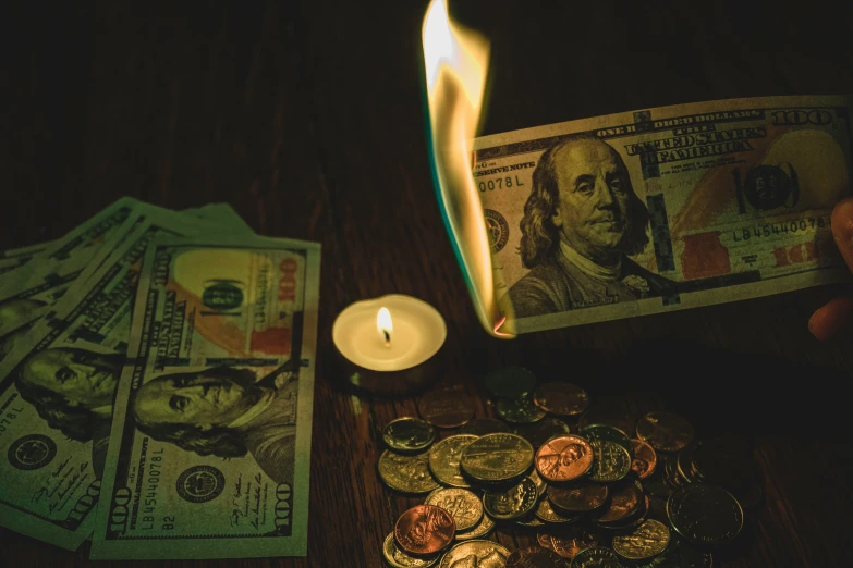 a table with stacks of money, a candle and one candle stick