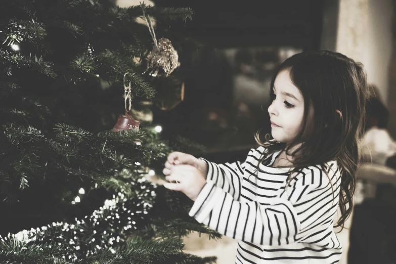 the little girl is putting ornaments on the christmas tree