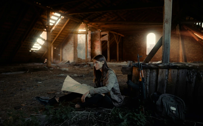 a woman sits inside a barn while reading a map