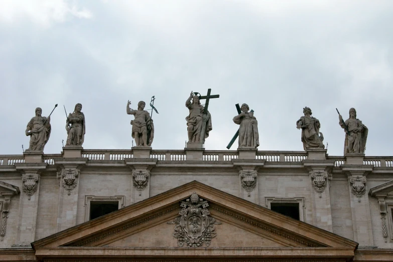 statues on the roof of a building against a cloudy sky