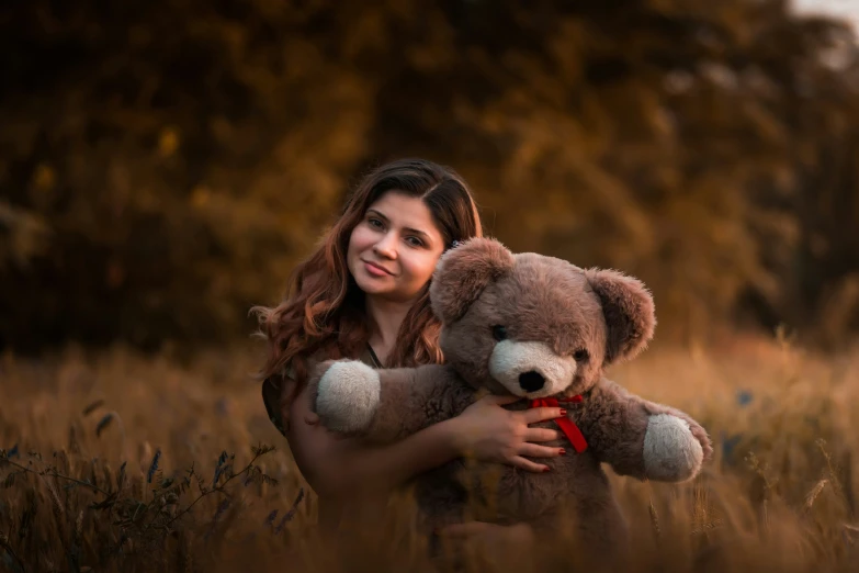 the young woman is holding a teddy bear in her hands