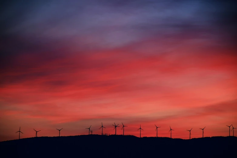 a cloudy sunset with windmills behind it