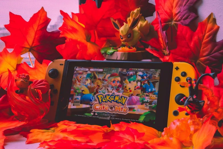 a nintendo lite with the new pokemon let's play logo in front of autumn leaves