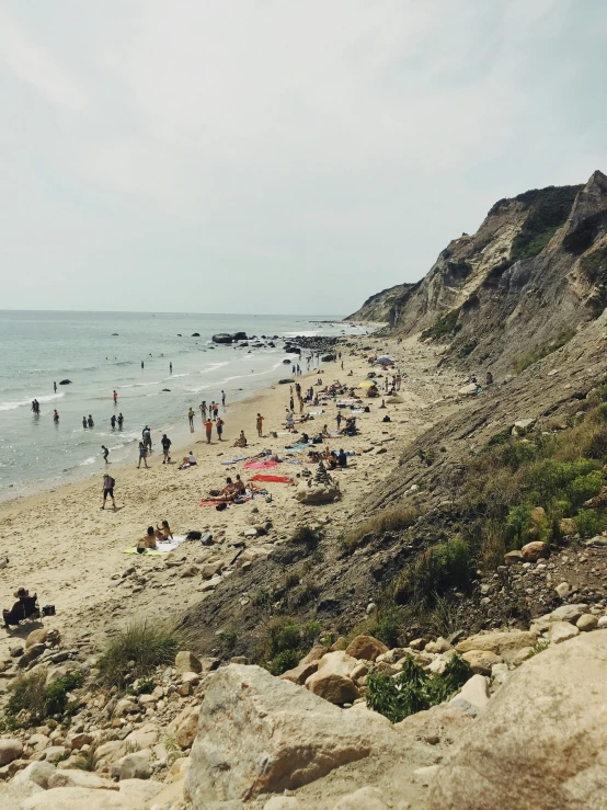 beach full of people with umbrellas and water in background