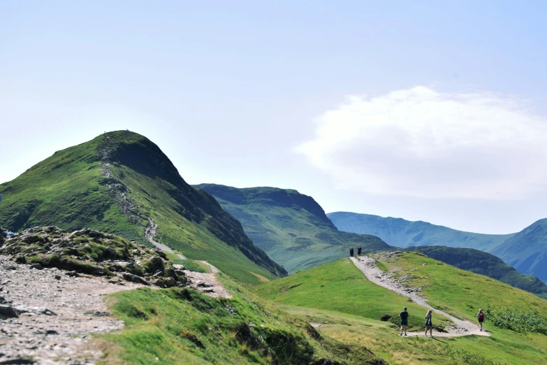 some people walking up a hill with mountains in the background