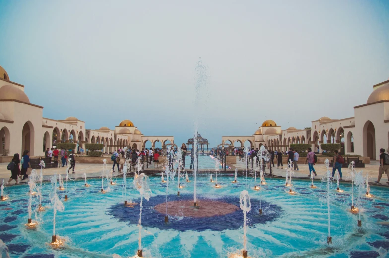 a crowd of people walking around a fountain