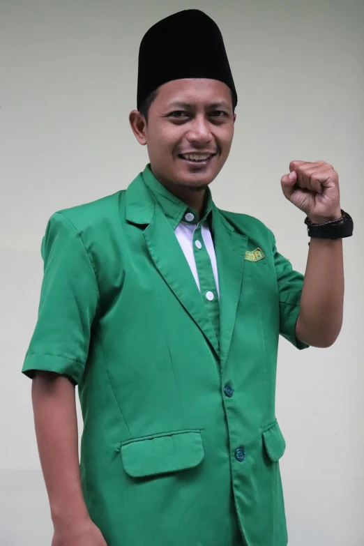 a man wearing a green blazer and white shirt posing