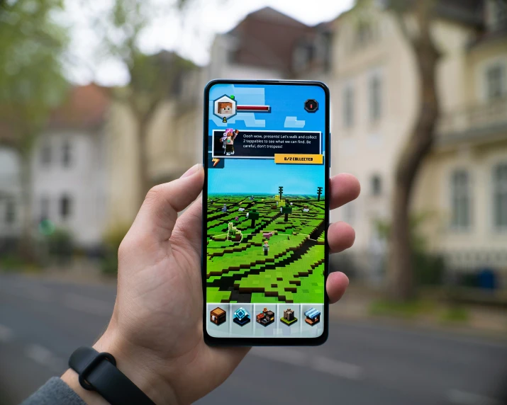 a person holds up a cell phone in front of houses