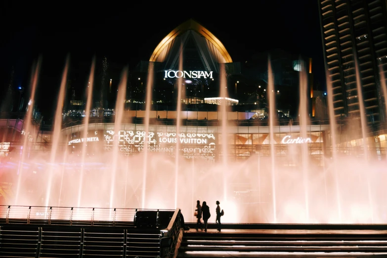 the fountain show at night near some buildings