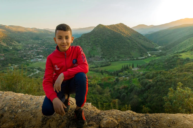 a boy sitting on top of a tree log