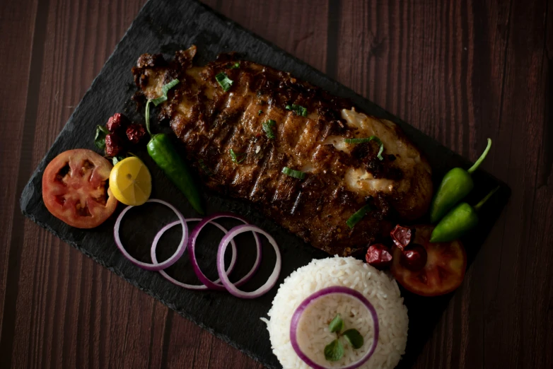 cooked meat and veggies sit on a black surface